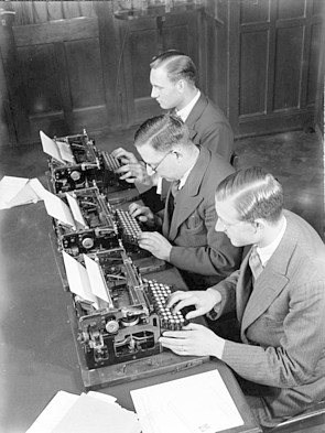 Foto van mannen aan schrijfmachines in de werkkamer van de administratie